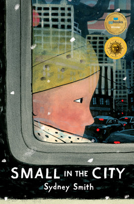  It is snowing. An up-close view of the corner of a bus window shows a child with light skin tone sitting inside right next to the window. They wear a hat and scarf. Inside the window are the silhouettes of people standing and holding on to the bus railings. A busy city street with cars stopped at a red light and tall buildings are in the reflection of the window. Text: Small in the city. Sydney Smith. 