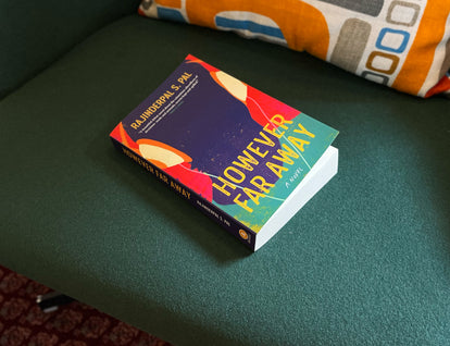 A photograph of a copy of However Far Away sitting on a green chair. 