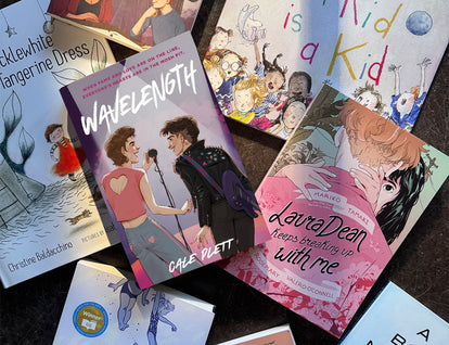 A photo of Pride Month titles from Groundwood arranged on a concrete backdrop. 
