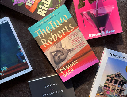 A collection of various House of Anansi books for pride arranged on a concrete background. The two Roberts by Damian Barr is in the centre.  