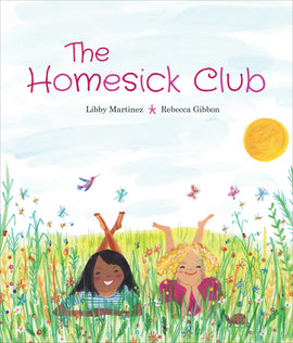  A grassy meadow has colourful wildflowers growing in it. Two girls, one with dark skin tone and one with light skin tone, smile and lay on their stomachs side-by-side in the grass. Their feet are up in the air. Around them are butterflies, a hummingbird, and a turtle. Text: The Homesick Club. Libby Martinez. Rebecca Gibbon. 